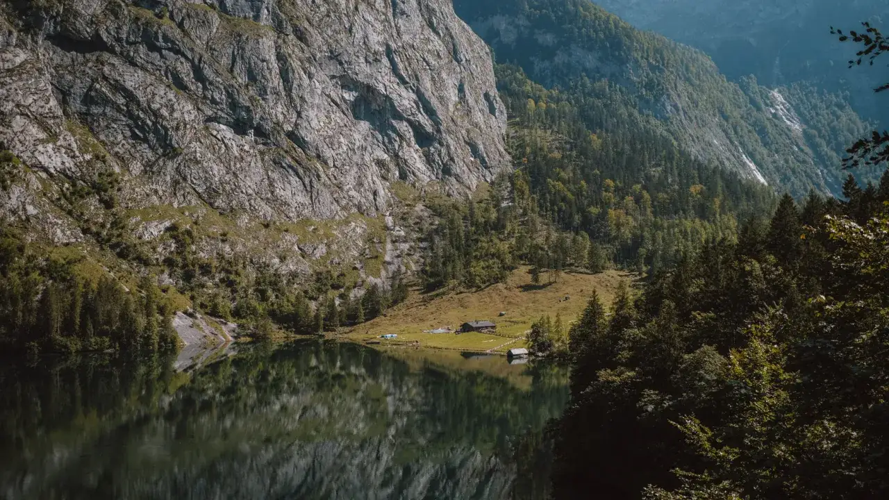 Majestätische Felswand spiegelt sich im ruhigen Wasser des Obersee. Kleine Häuser am Ufer, umgeben von grünen Wäldern.