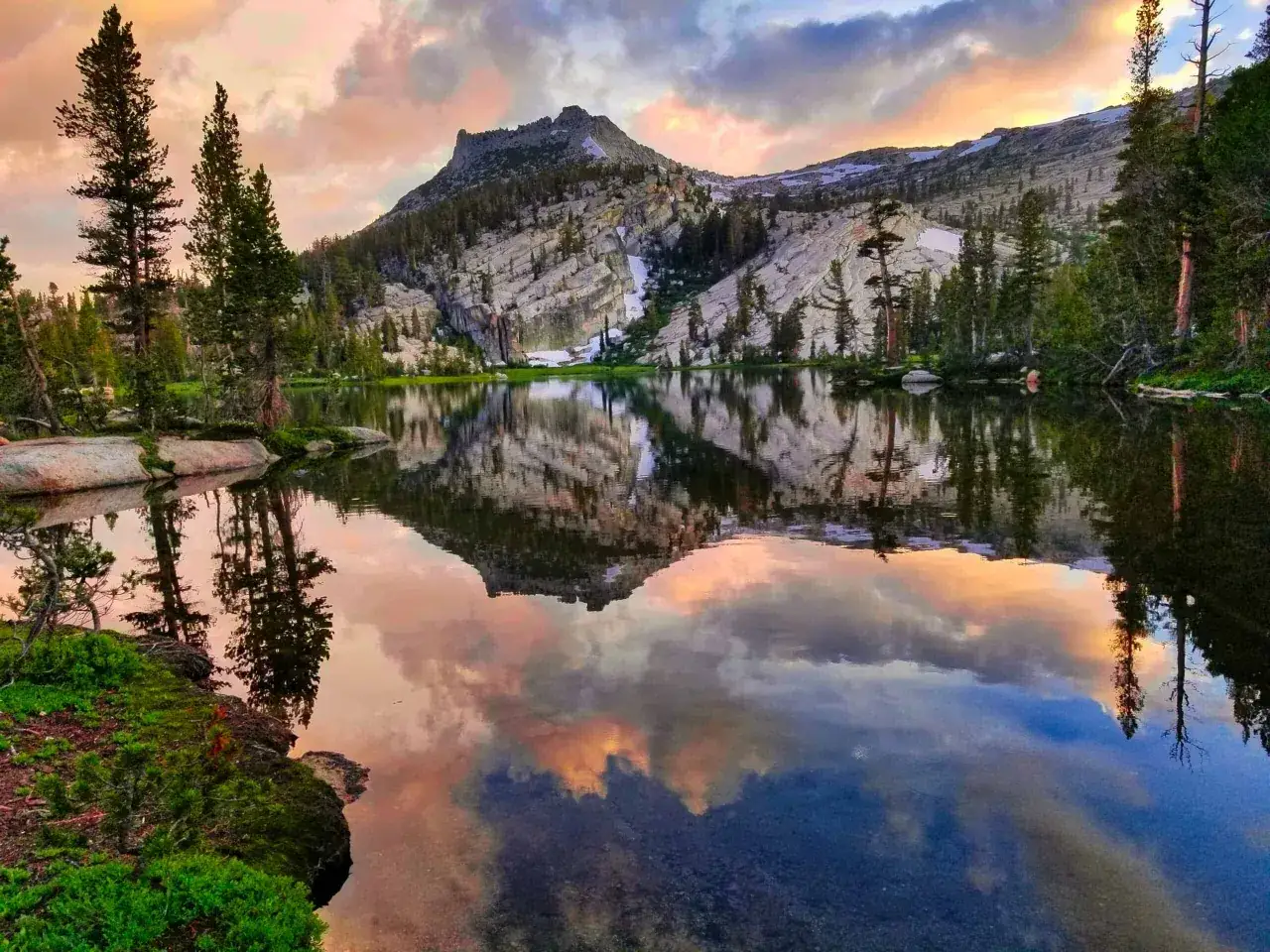 Reflejo de monta&ntilde;a y cielo al atardecer en un lago sereno, parte del John Muir Trail.