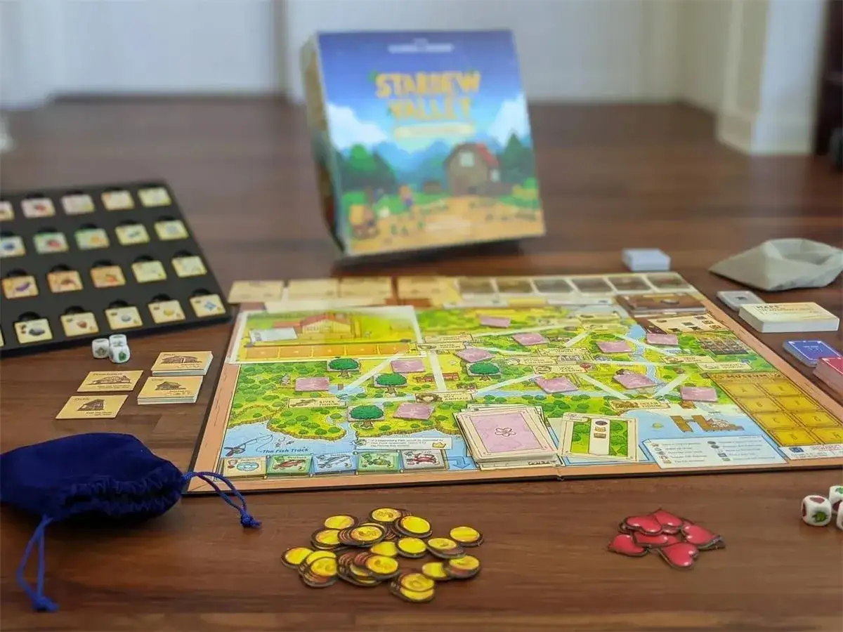 Stardew Valley gra planszowa na drewnianym stole. Widoczne elementy gry: plansza, karty, kostki, woreczek i żetony.