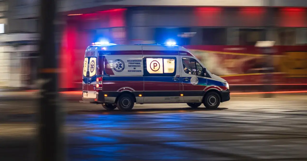 Pojazd uprzywilejowany, karetka pogotowia ratunkowego w Katowicach, pędzi nocą z włączonymi niebieskimi światłami.