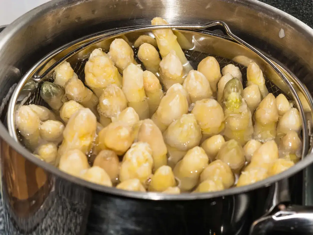 Spargel im Spargeltopf kochen. Die weißen Stangen garen in siedendem Wasser, bereit für ein Frühlingsgericht.