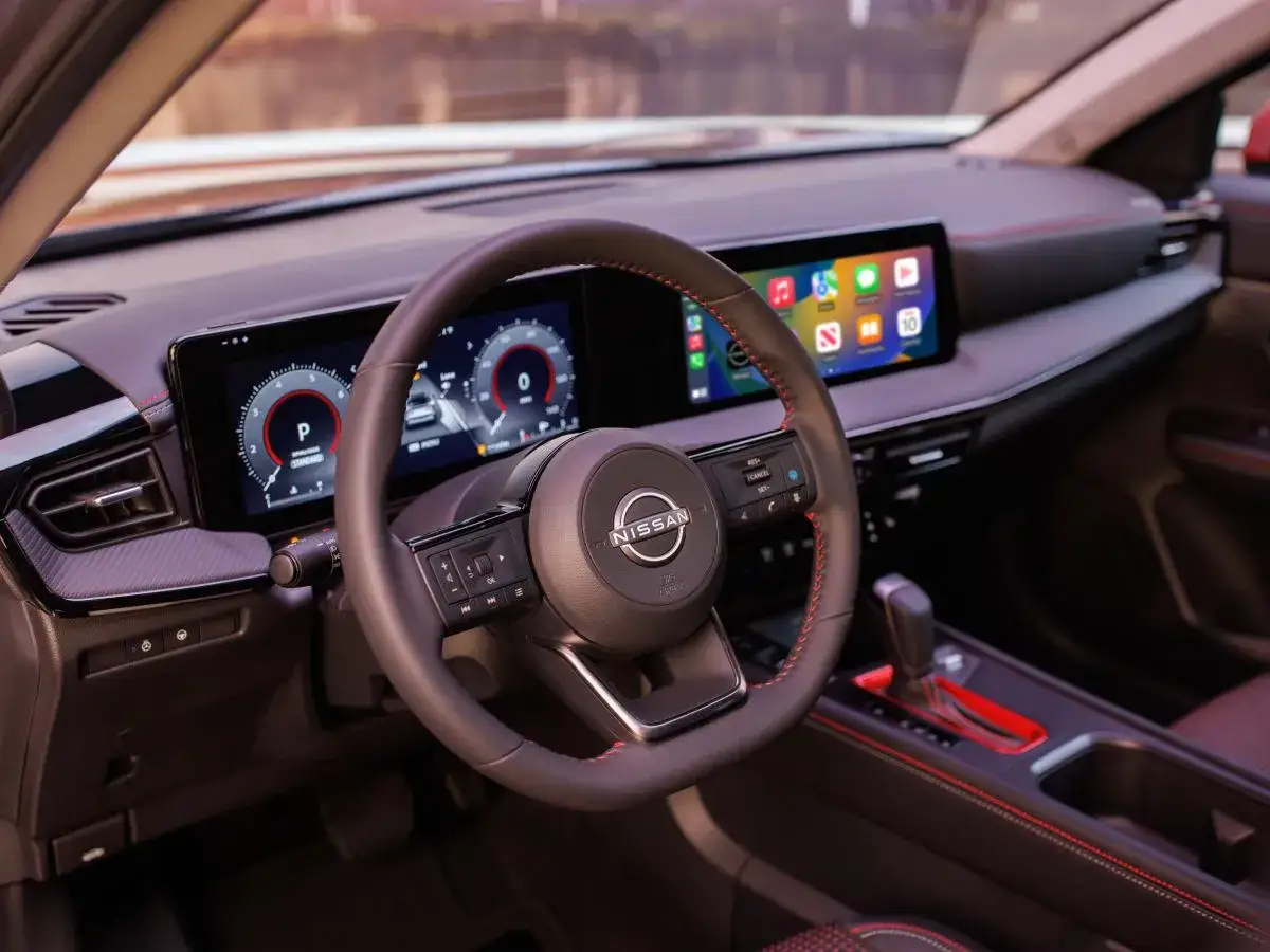 Wnętrze nowego Nissan Kicks z cyfrowymi zegarami i ekranem multimedialnym. Czerwone przeszycia dodają sportowego charakteru.