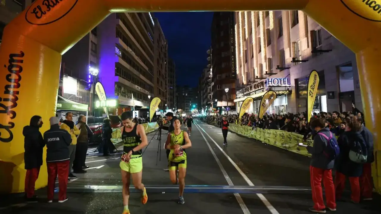 Corredores cruzan la meta en el recorrido San Silvestre Zaragoza. El ambiente nocturno y la iluminación realzan la emoción de la carrera.