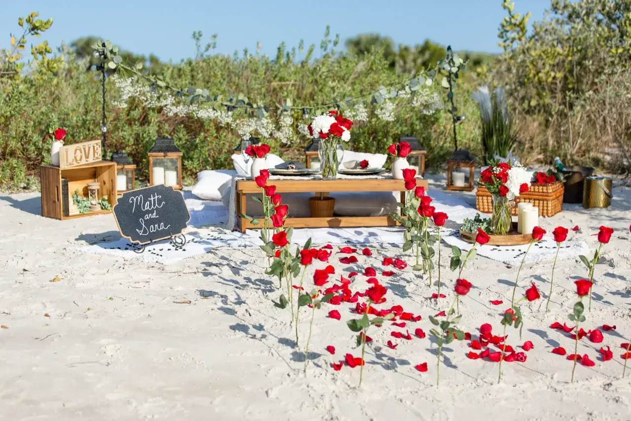 Romantyczne oświadczyny na plaży z płatkami róż i napisem 