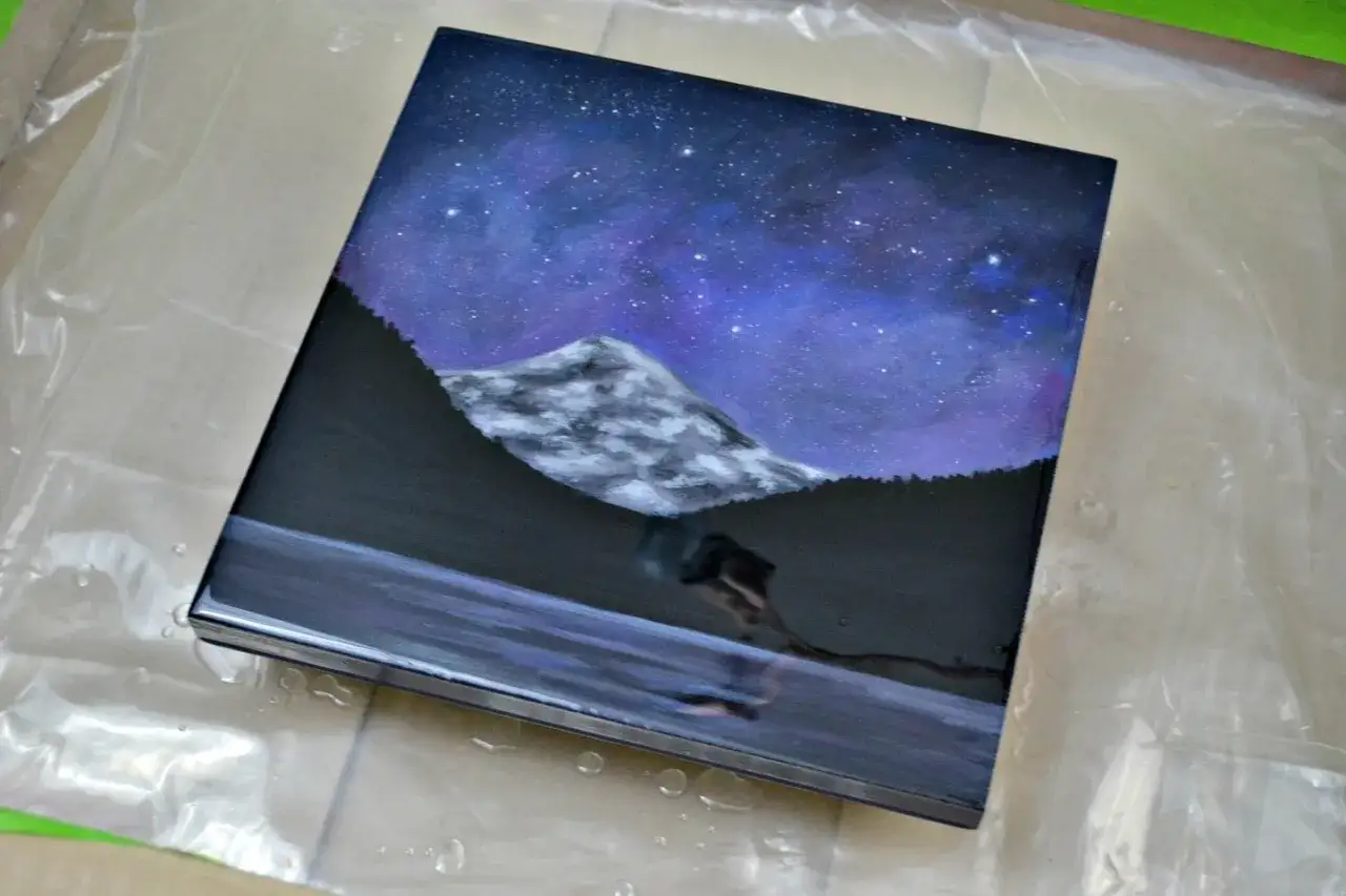Peinture acrylique d'un paysage nocturne avec montagne et étoiles, recouverte d'une couche de résine brillante. Peut-on mettre de la résine sur de la peinture acrylique ? Oui !