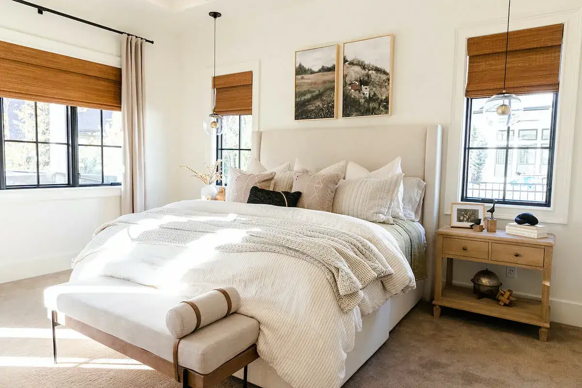 Cozy bedroom makeover on a budget. Sunlight streams into a serene room with a plush bed, textured throws, and natural wood accents.
