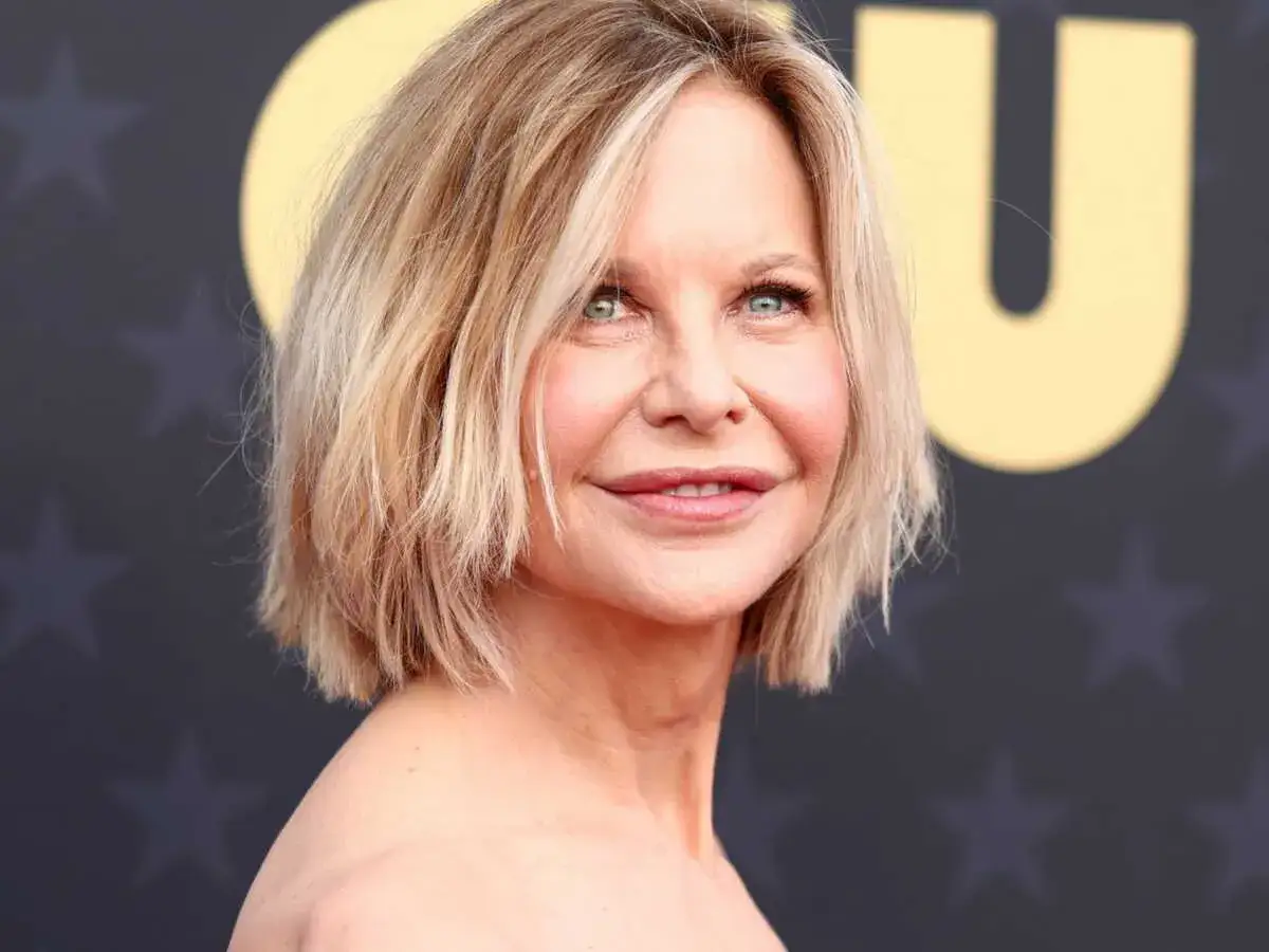 Une femme de 50 ans avec une coupe courte et dégradée, parfaite pour des cheveux fins et plats, souriant légèrement.