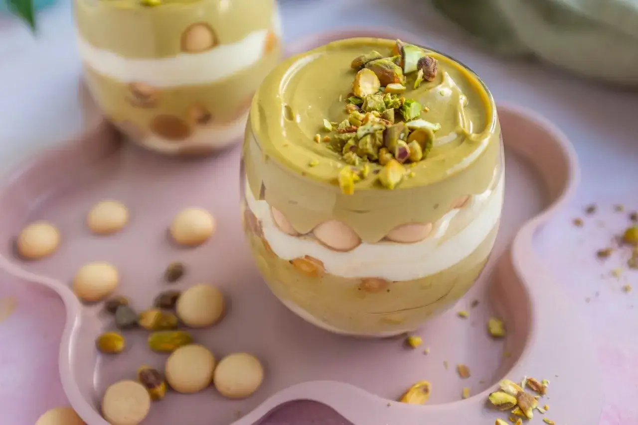 Pyszny deser z warstwami kremu pistacjowego z mascarpone, ciasteczek i posypką z orzechów pistacjowych.