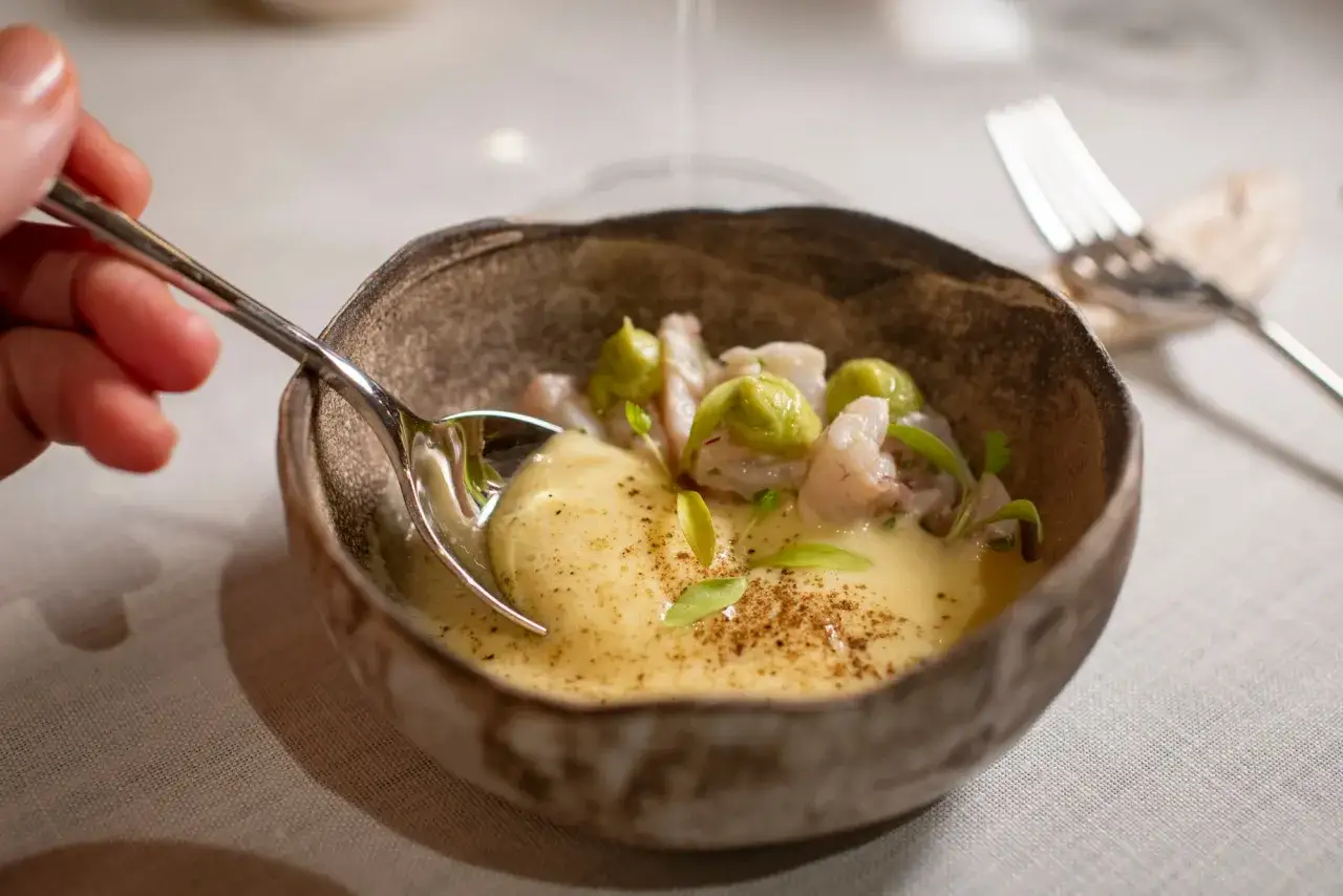 Un plato de gambas con aguacate y salsa cremosa, parte de un men&uacute; degustaci&oacute;n.