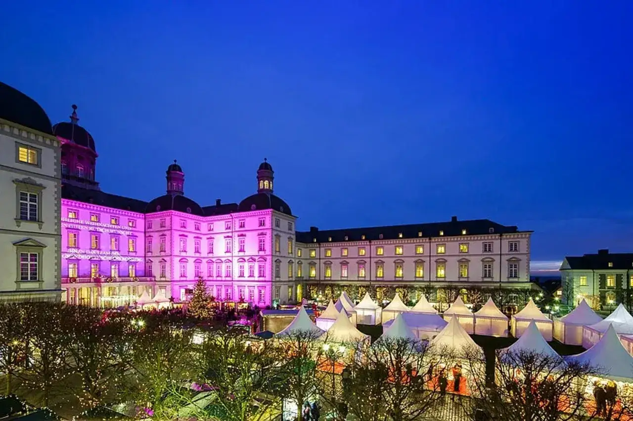 Festlicher weihnachtsmarkt schloss bensberg im Abendlicht mit beleuchtetem Schloss und vielen Buden.