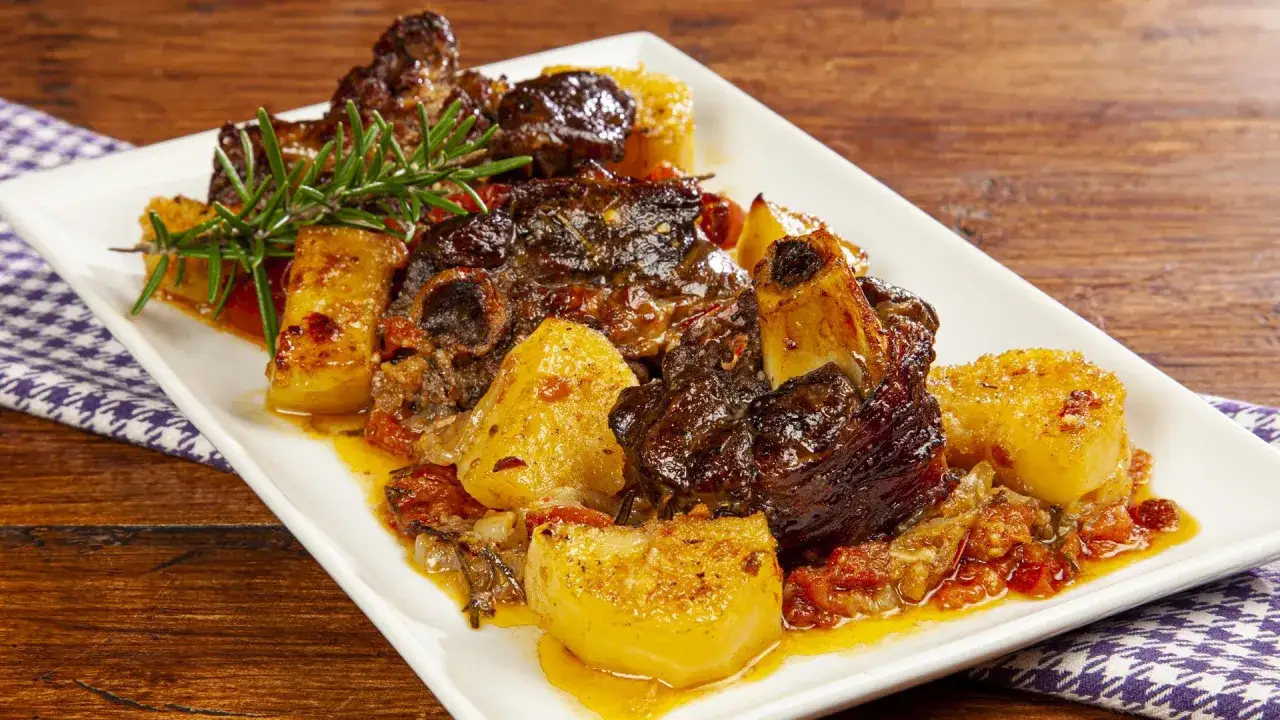 Succulento agnello al forno con patate arrosto e rosmarino, un piatto che profuma di tradizione e sapori autentici.