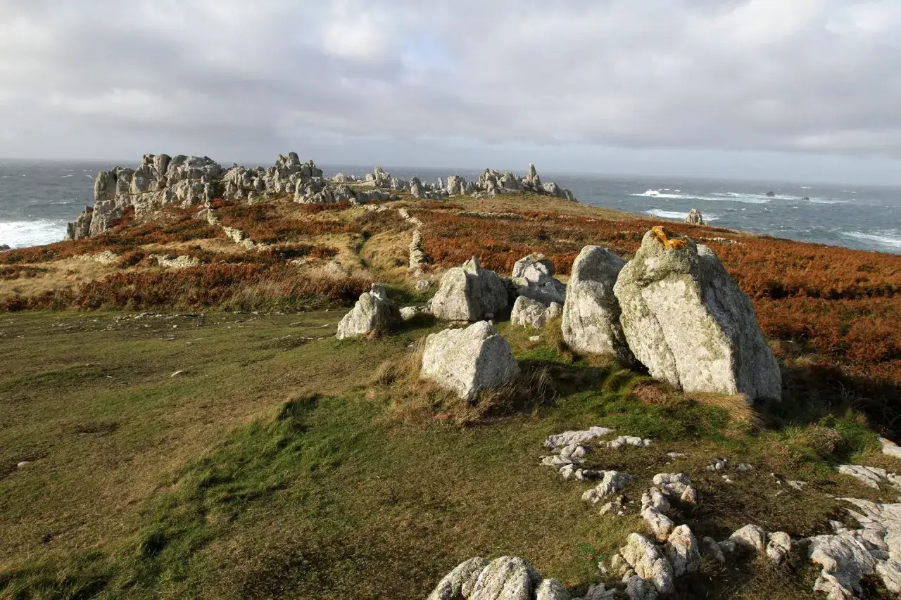 Paysage rocheux et côtier d'Ouessant, avec des fougères rousses et la mer agitée. Combien de temps pour visiter Ouessant ? Une journée suffit pour admirer cette beauté sauvage.