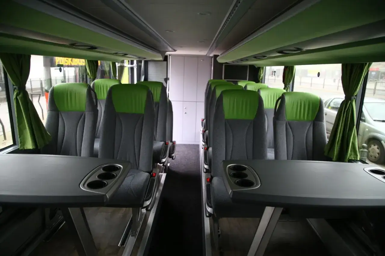 Wnętrze autokaru FlixBus z rzędami szarych siedzeń i zielonymi zagłówkami. Stoliki z uchwytami na kubki. Ile miejsc w autokarze?