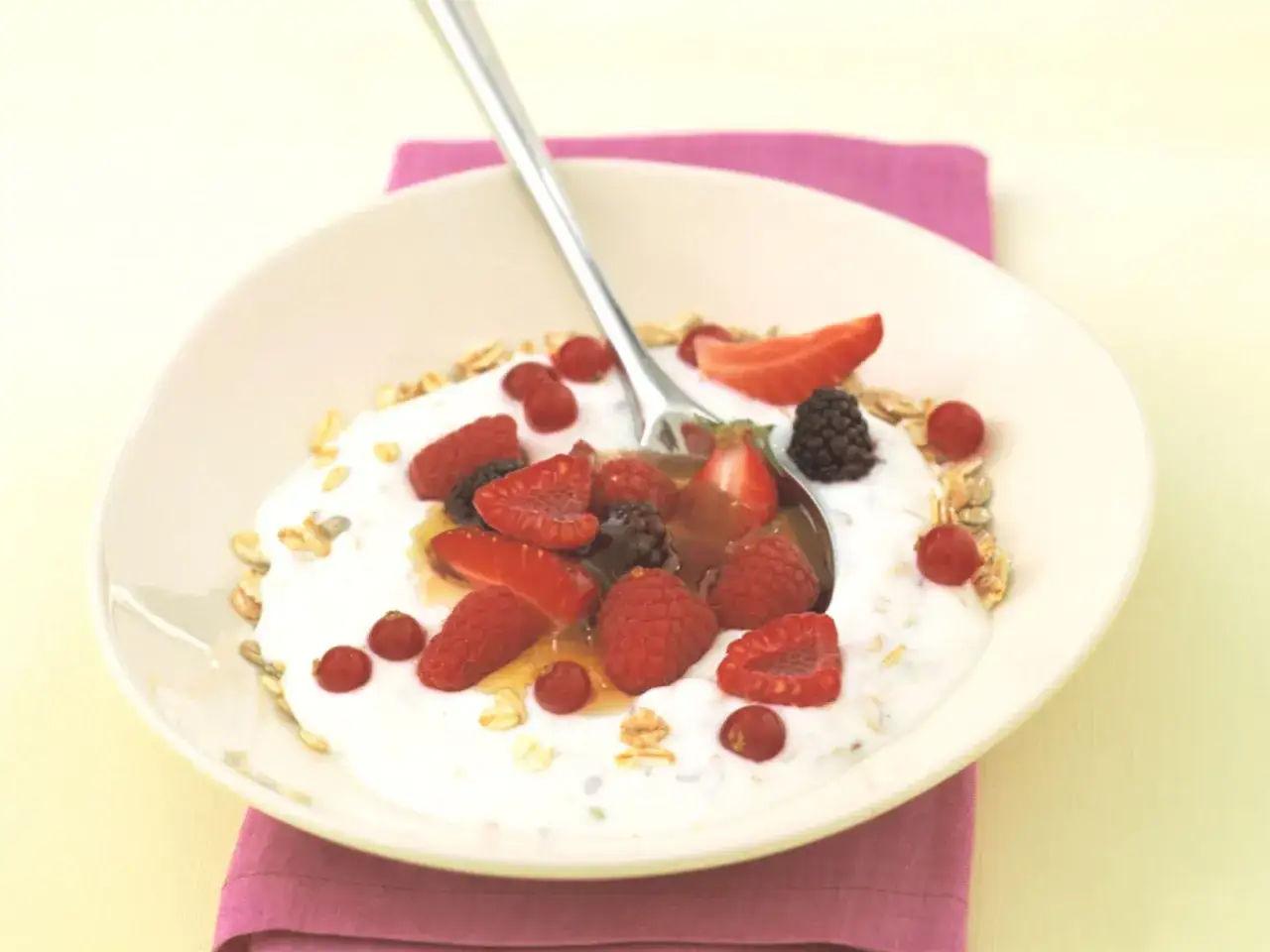 Schüssel mit Haferflocken, Kefir und frischen Beeren. Ein Löffel mit Honig und Früchten. Gesundes Frühstück.