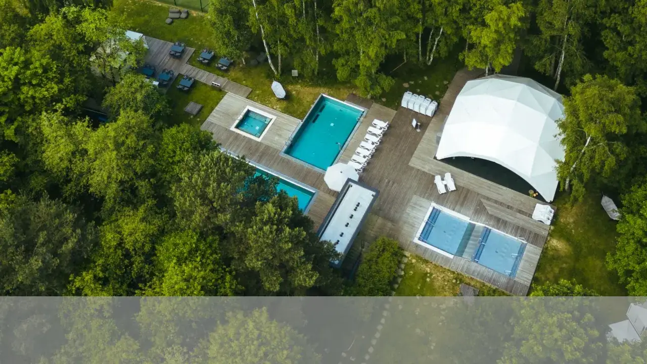 Fajny hotel nad morzem otoczony zielenią, z basenami, leżakami i białym namiotem. Idealne miejsce na relaks.