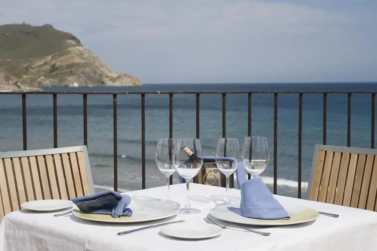Mesa lista para cenar en Doña Pakyta restaurante, con vistas al mar y una botella de vino enfriándose.