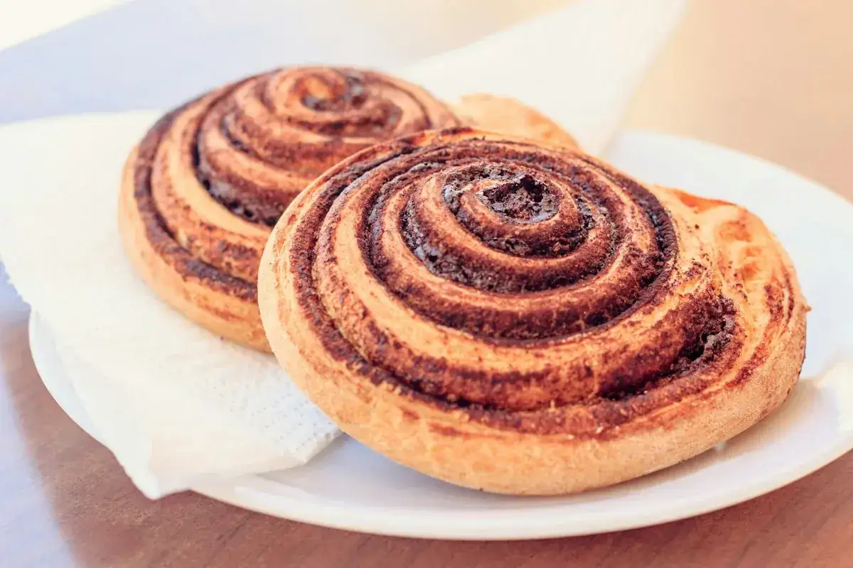 Två kanelbullar på en vit tallrik, perfekta för vegetariska recept.