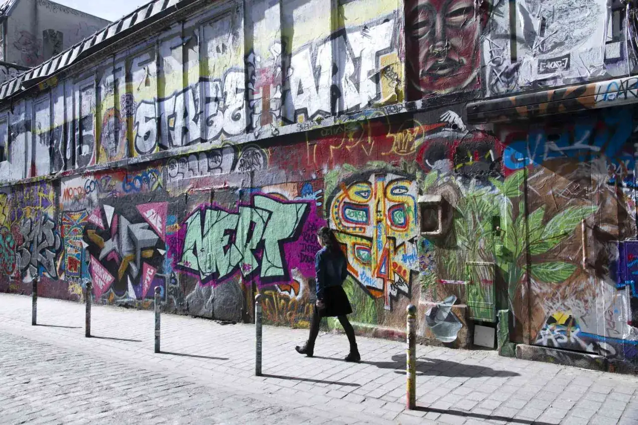 Bunte **Paris street art** bedeckt eine Wand, w&auml;hrend eine Person vorbeigeht.