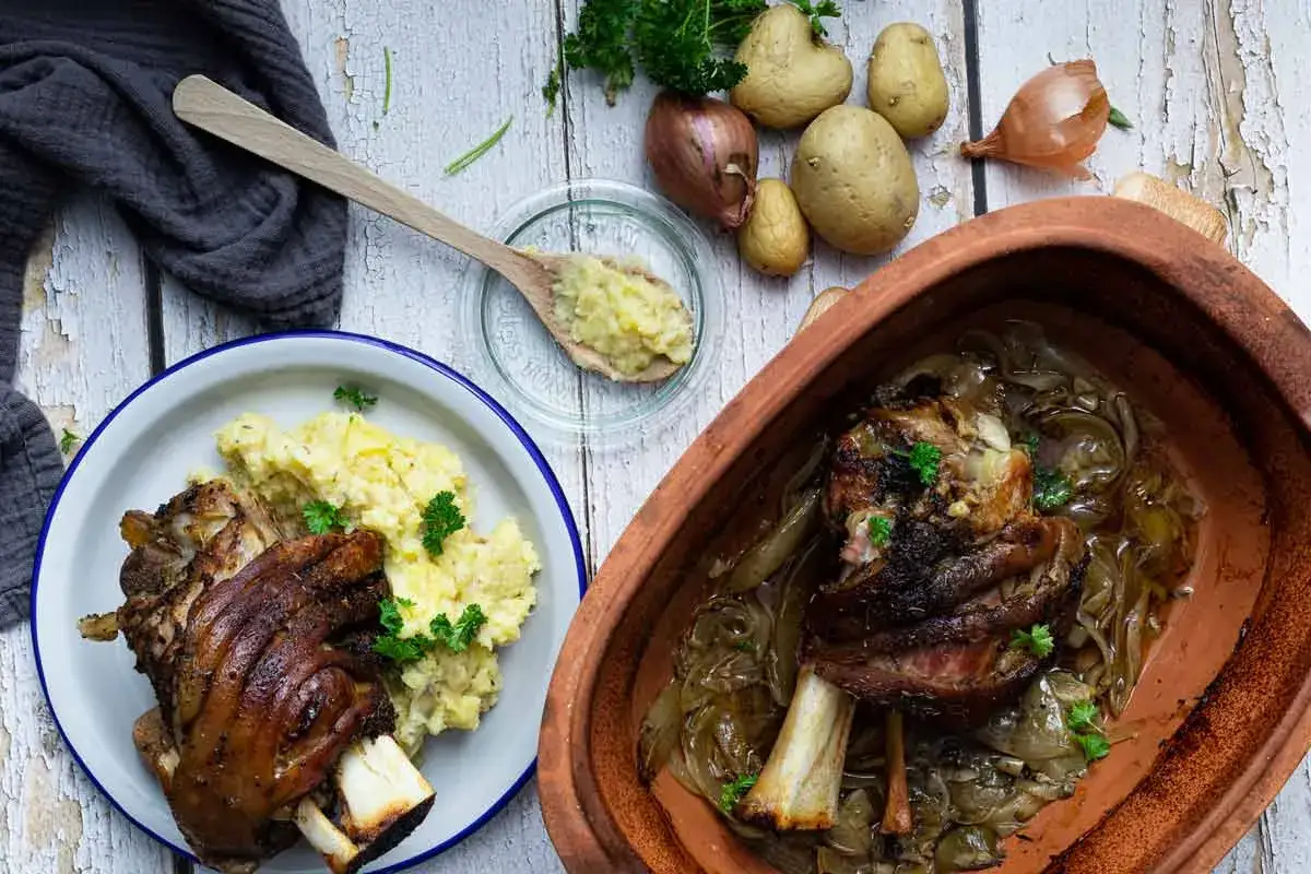Knusprige Schweinshaxe mit Kartoffelpüree und Zwiebeln, bereit zum Servieren. Ein herzhaftes Gericht, das Lust auf mehr macht.
