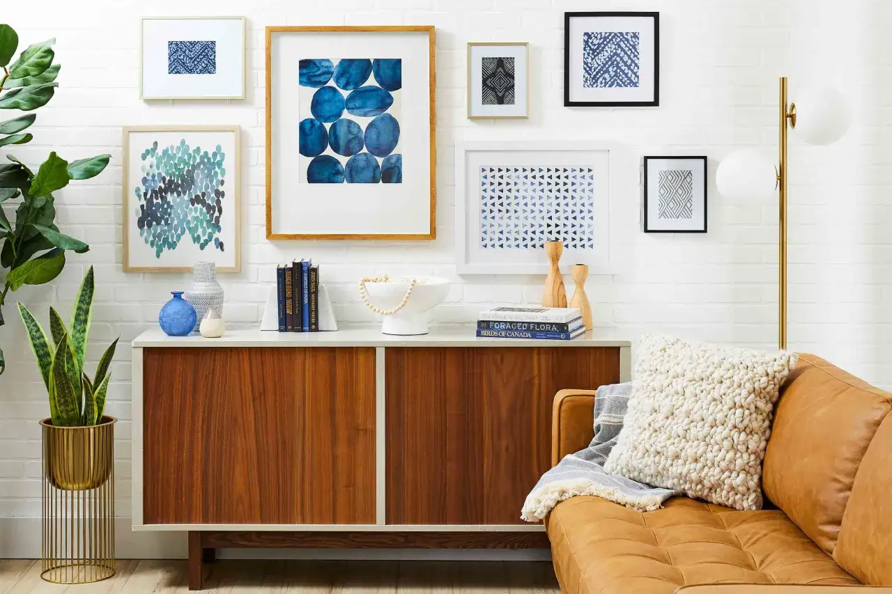 A stylish gallery wall features abstract blue art, geometric prints, and a framed textile.