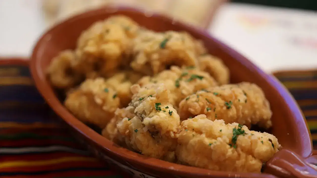 D&eacute;licieux beignets de poisson, sp&eacute;cialit&eacute; du restaurant Mad&egrave;re, servis dans un plat en terre cuite, parsem&eacute;s de persil frais.