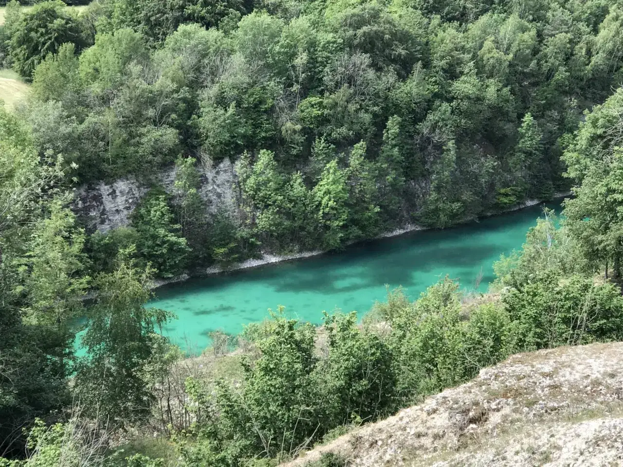 Eine malerische blaue Lagune im Teutoburger Wald, umgeben von &uuml;ppigem Gr&uuml;n und Felsformationen.