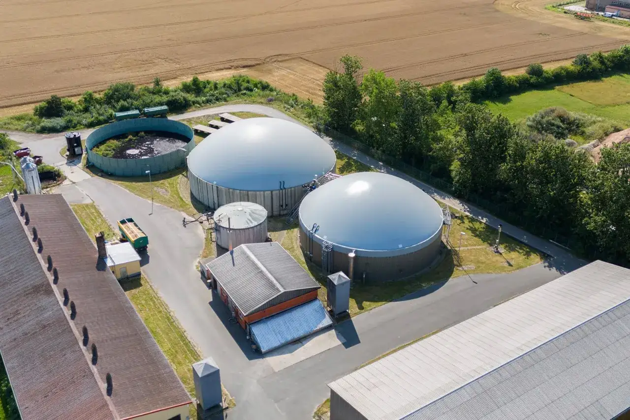 Zwei große, kuppelförmige Biogasanlagen und ein runder Behälter auf einem Bauernhof, der zur Energieversorgung von energieautarke gemeinden deutschland beiträgt.