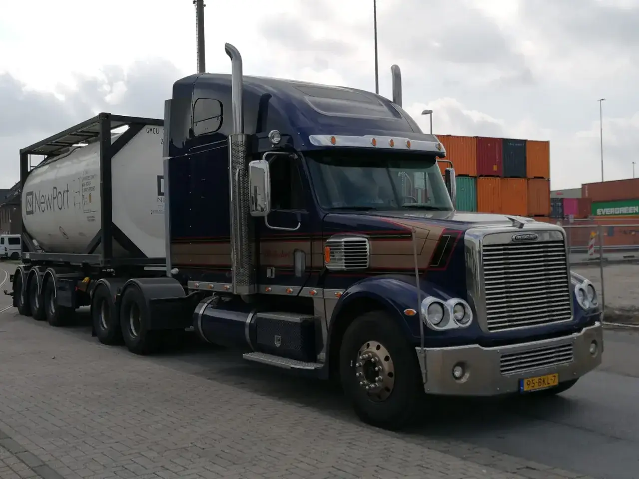 Un camion américain bleu foncé avec une remorque citerne blanche, prêt à transporter des marchandises.