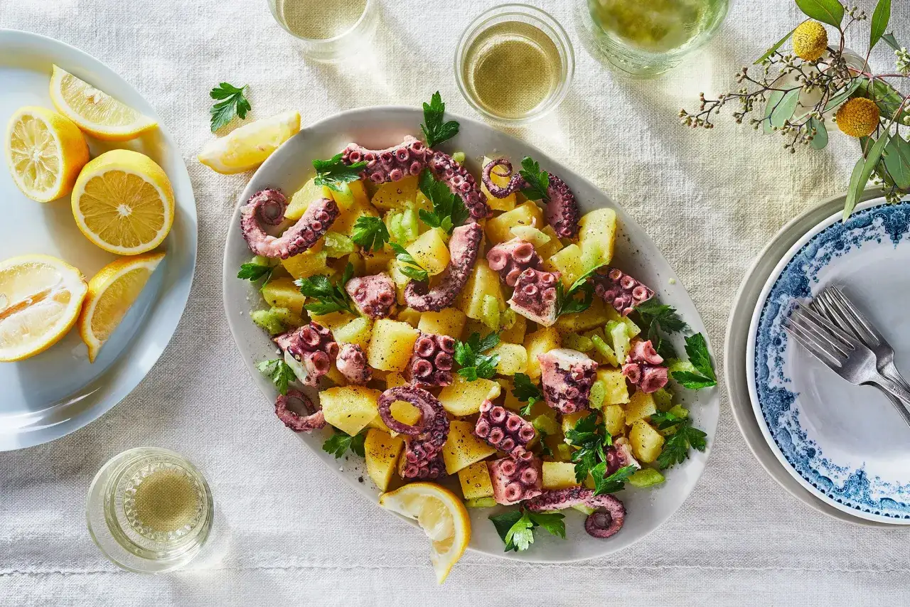 Ein köstlicher Pulpo Salat Original mit Kartoffeln, Sellerie und frischer Petersilie, garniert mit Zitronenspalten.