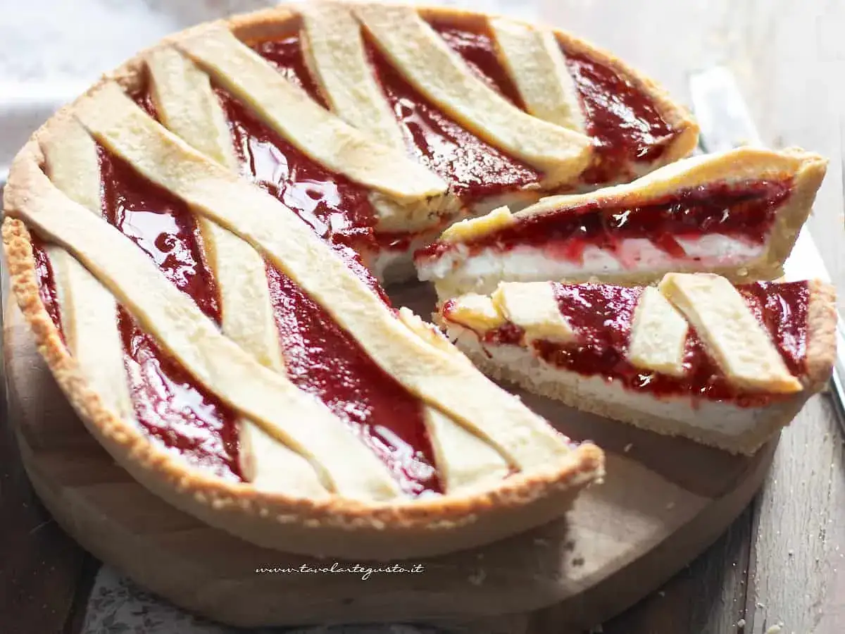 Una deliziosa crostata ricotta e marmellata, con una fetta tagliata per mostrare il ripieno cremoso e la crosta dorata.