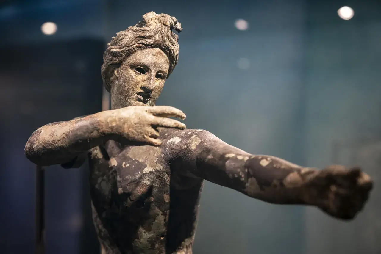 Statua bronzea ritrovata nel santuario di San Casciano dei Bagni, con dettagli del volto e delle braccia.