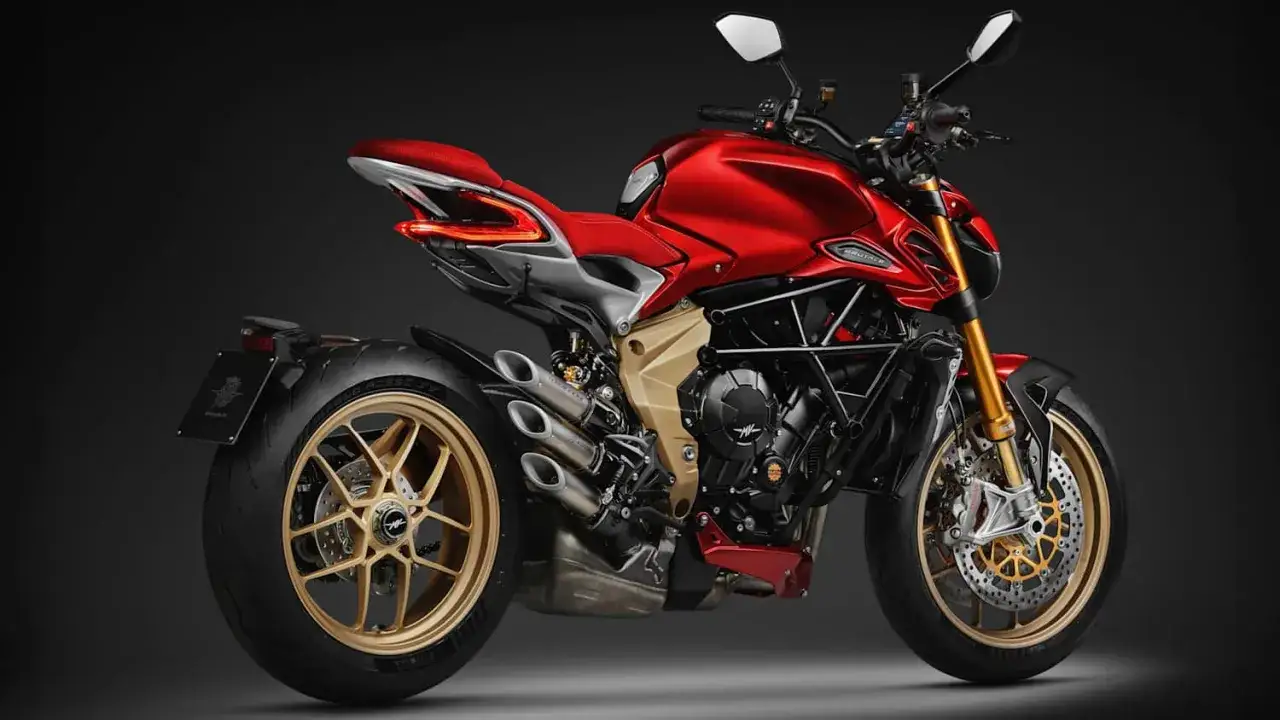 Ein rotes retro Motorrad mit goldenen Felgen und Auspuffrohren steht vor einem dunklen Hintergrund.