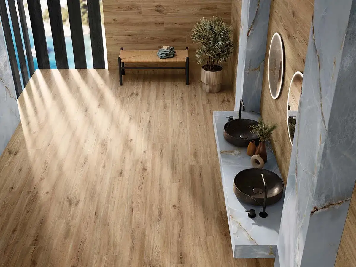 Ba&ntilde;o moderno con suelo de porcelanato de 120x20 imitando madera, lavabos sobre encimera y detalles en m&aacute;rmol azul.