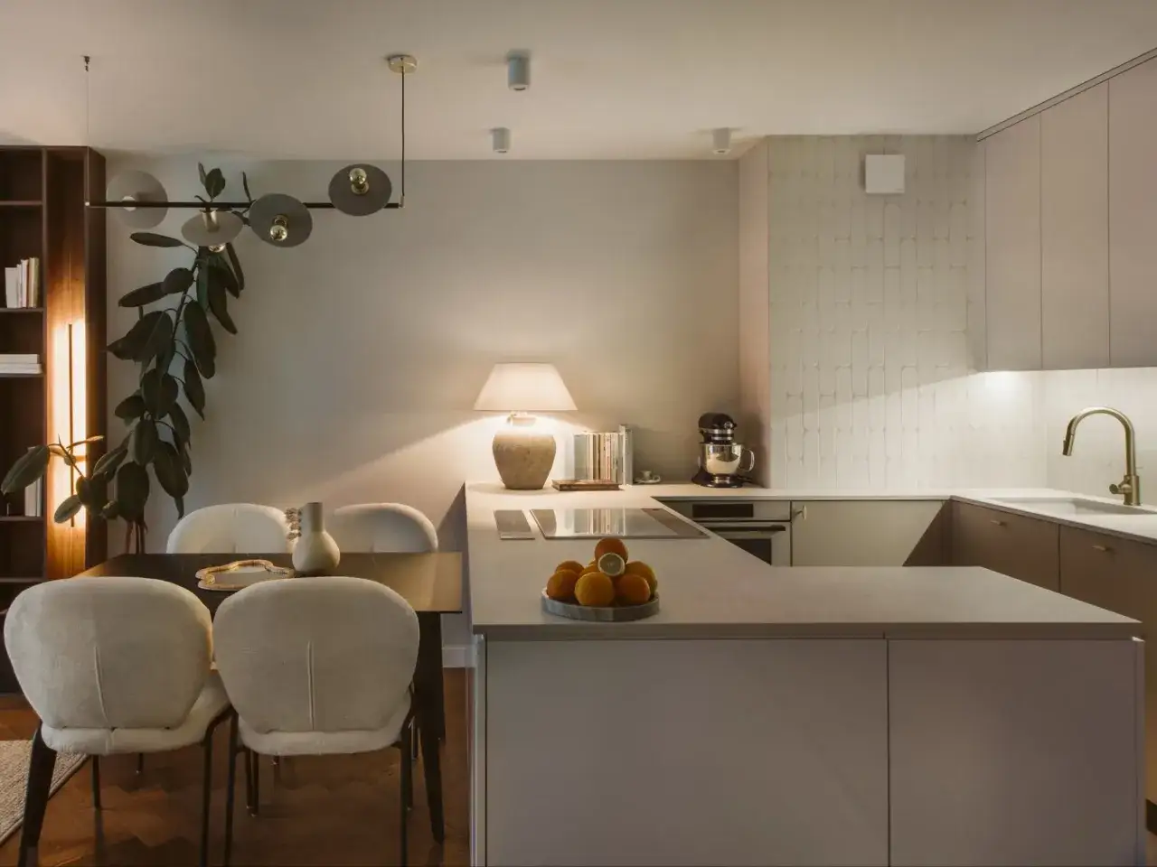 Nowoczesny dom dla singla: kuchnia z wyspą, jadalnia z wygodnymi krzesłami i designerska lampa.