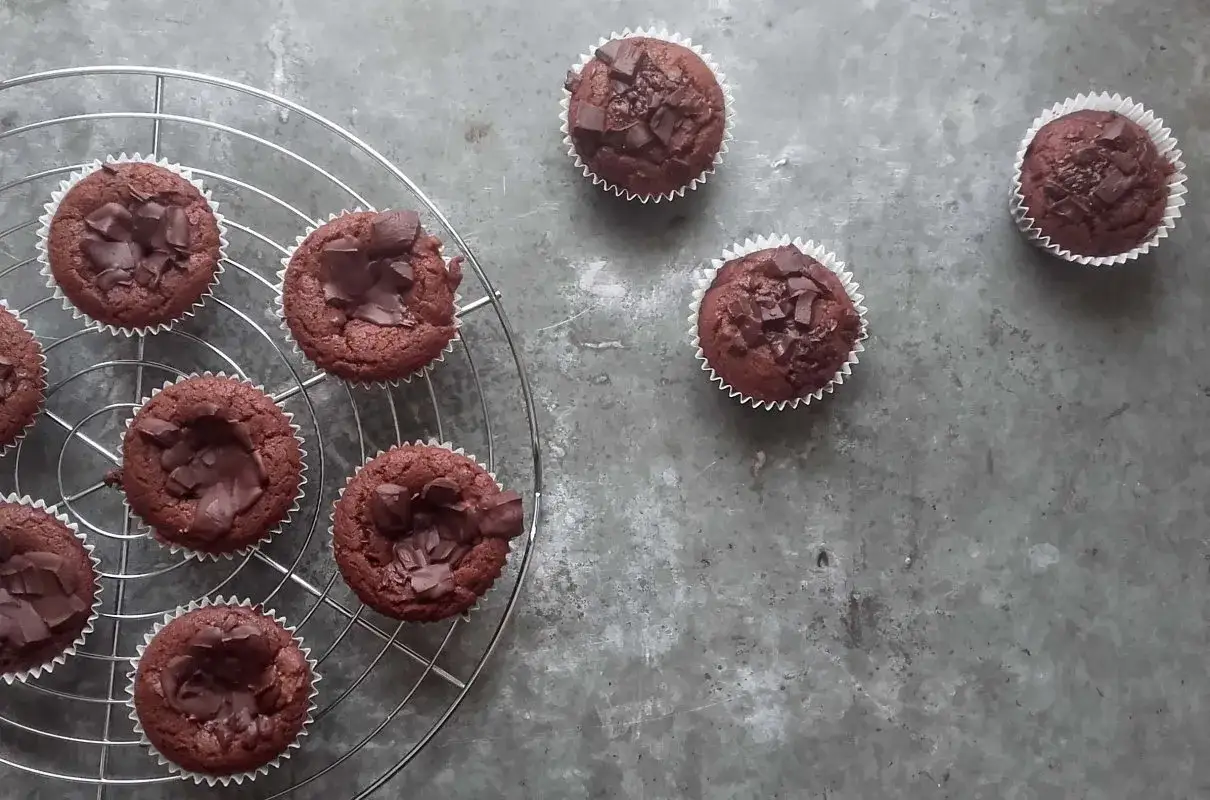 Pyszne babeczki brownie, udekorowane kawałkami czekolady, stygną na kratce.