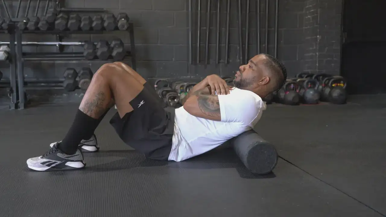Man ligger på en foam roller i ett gym för att mjuka upp fascian.
