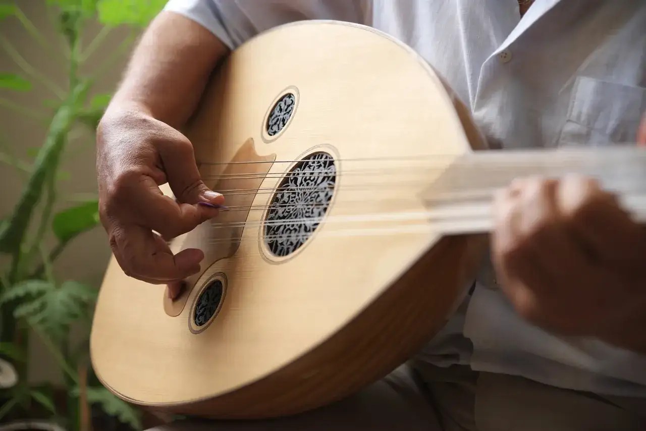 Un musicien joue d'un oud, instrument &agrave; cordes d'origine ancienne, dont les rosaces d&eacute;cor&eacute;es rappellent l'art oriental.