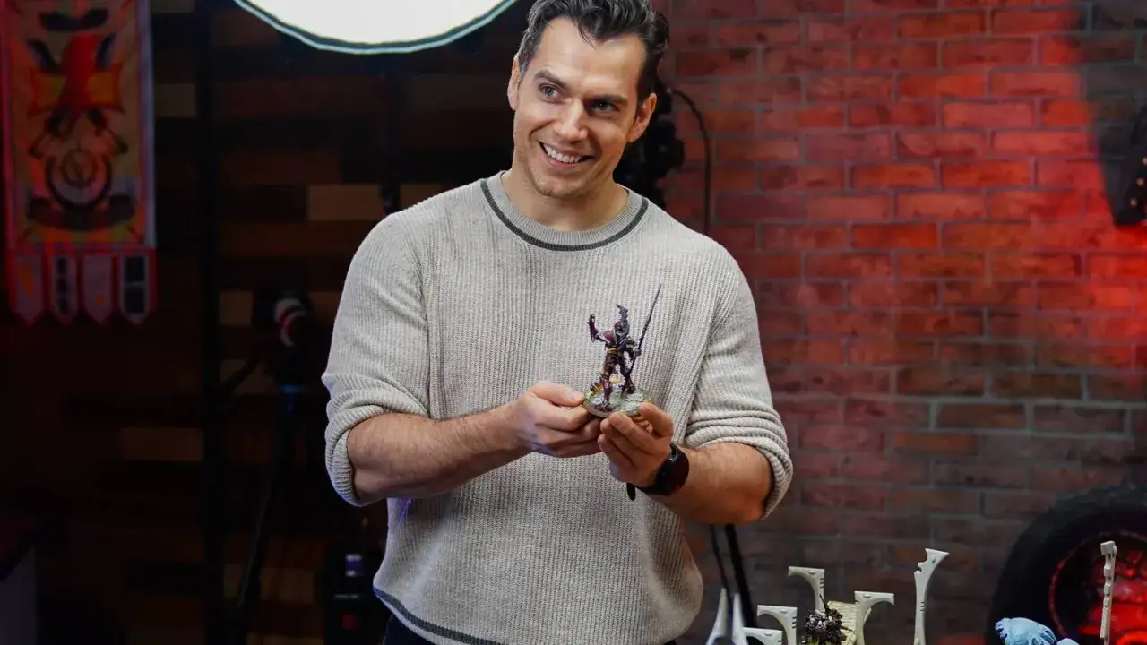 Henry Cavill z dumą prezentuje pomalowaną figurkę z Warhammera, gotową do bitwy.