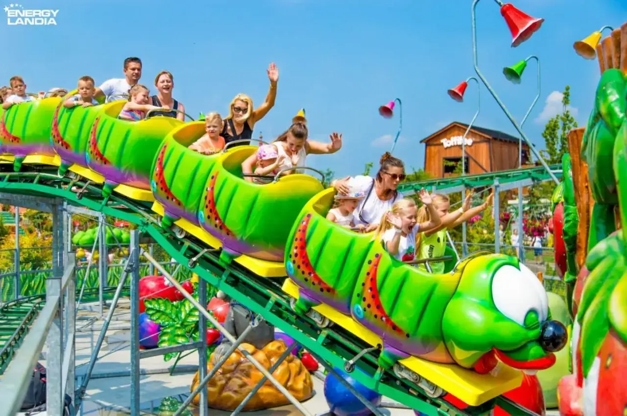 Rodzina śmieje się na zielonym rollercoasterze w kształcie gąsienicy w Energylandii. Od ilu lat można tu szaleć?