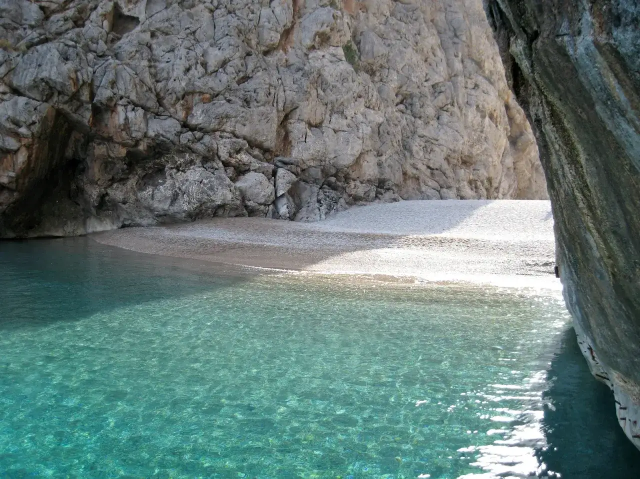 T&uuml;rkisblaues Wasser trifft auf Kiesstrand und Felsen. Perfektes Mallorca Wetter f&uuml;r eine versteckte Bucht.