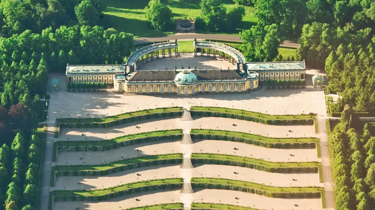 Luftaufnahme von Schloss Sanssouci, einem der sch&ouml;nsten Ausflugsziele Potsdams, mit terrassierten G&auml;rten und symmetrischen Gr&uuml;nfl&auml;chen.