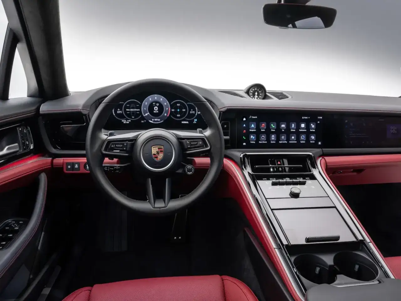 Wnętrze Porsche Panamera z czerwonymi skórzanymi akcentami, cyfrowymi zegarami i ekranem dotykowym.