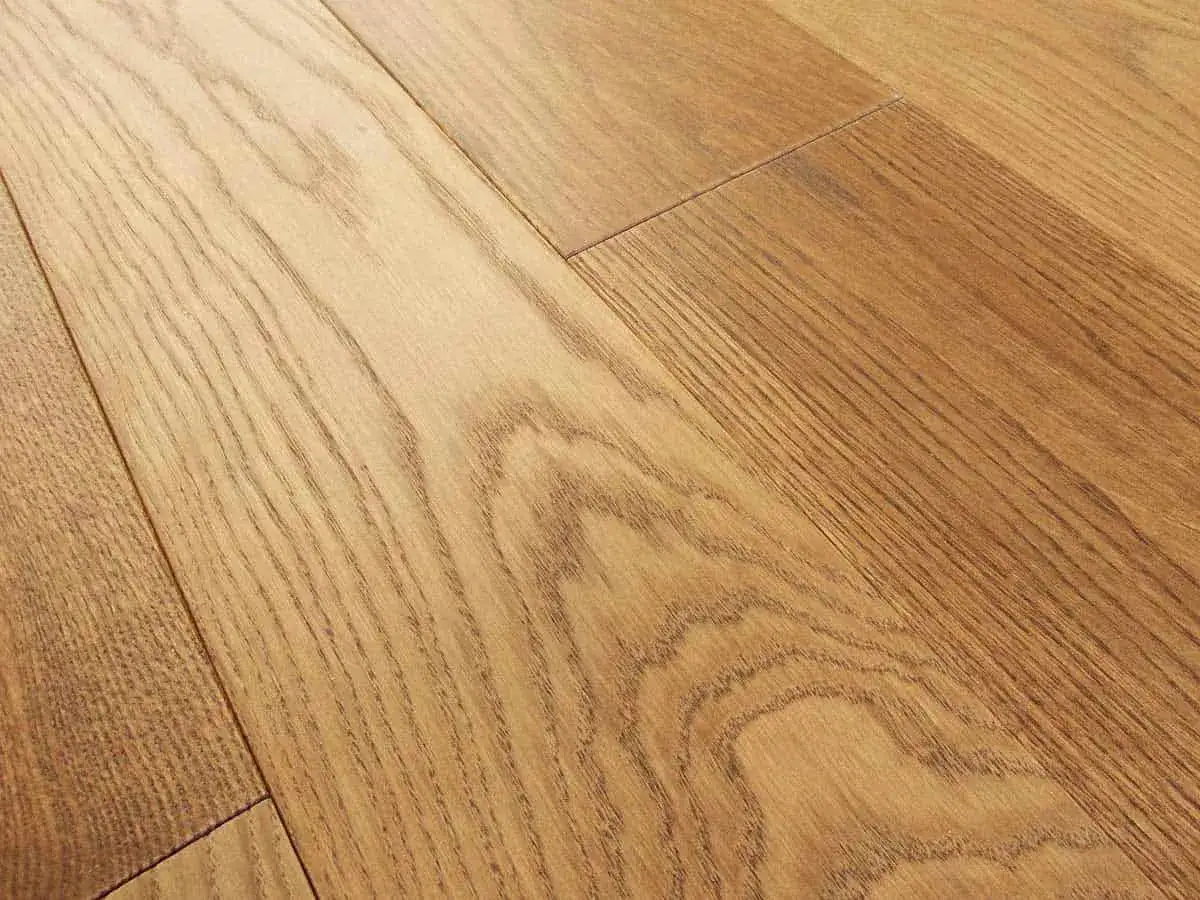 Detalle de un suelo laminado biselado de madera clara con vetas marcadas, creando un ambiente c&aacute;lido y natural.