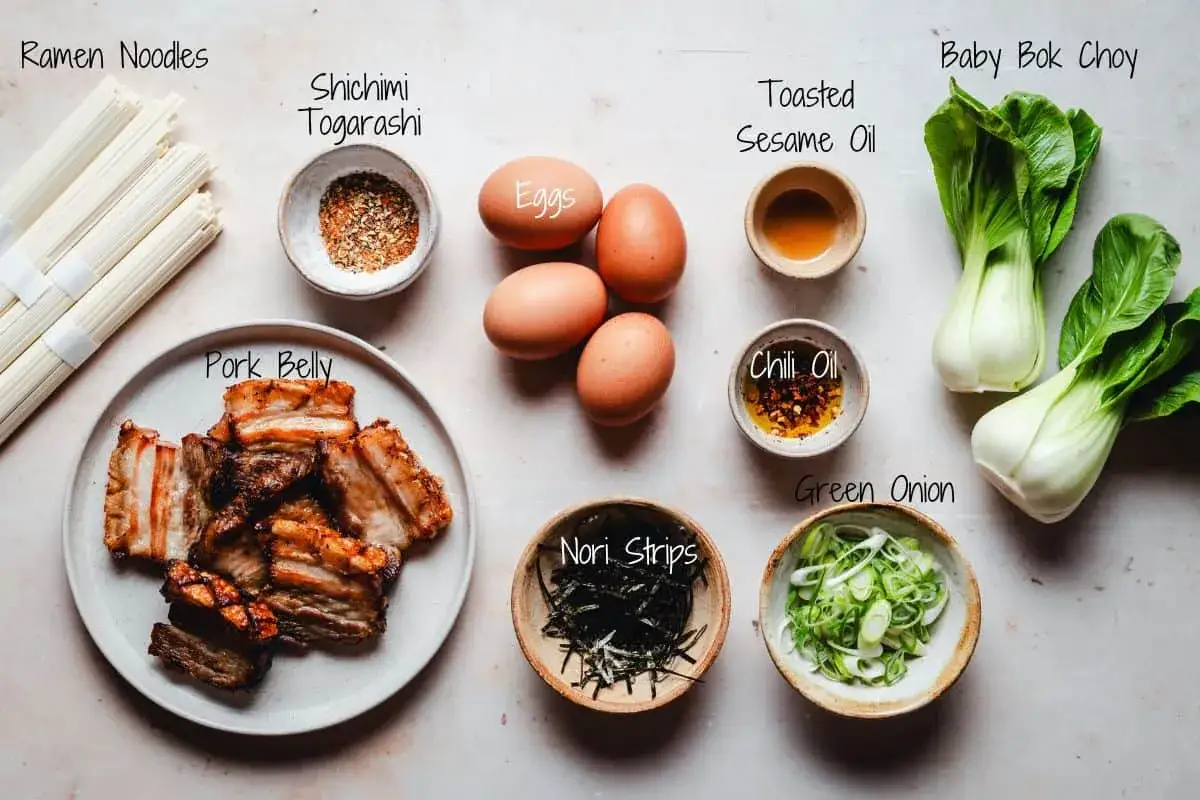 Zutaten f&uuml;r ein k&ouml;stliches Miso Ramen: Nudeln, Schweinebauch, Eier, Pak Choi, Fr&uuml;hlingszwiebeln, Nori, Shichimi Togarashi, Chili&ouml;l und Sesam&ouml;l.