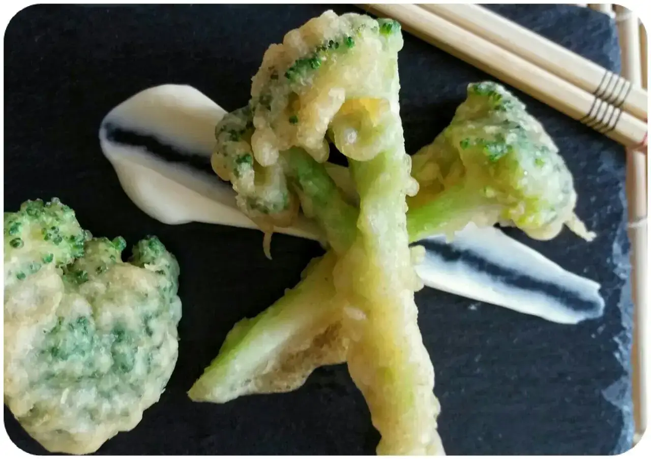 Crujiente br&oacute;coli en tempura, servido con una salsa cremosa y palillos.