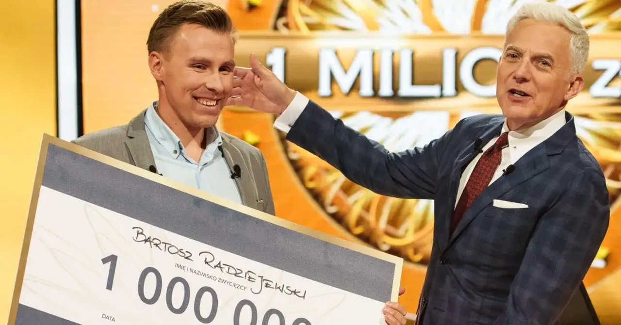 Bartosz Radziejewski, który wygrał milion w Milionerach, odbiera czek z nagrodą od prowadzącego.