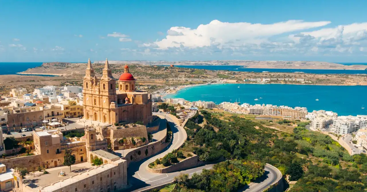 Malta, z kościołem i turkusowym morzem. Idealne miejsce, by zastanowić się, kiedy lecieć na Maltę.