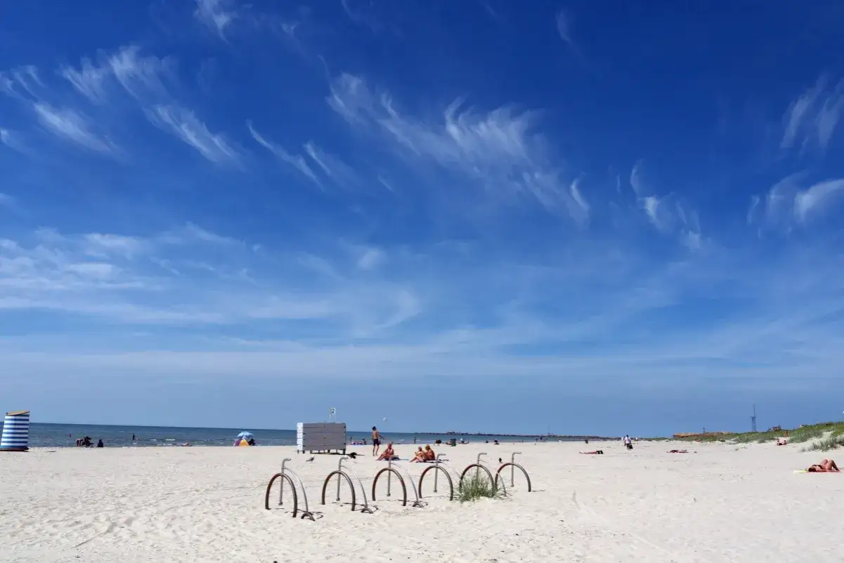 Piękny dzień nad litewskim morzem. Piaszczysta plaża, błękitne niebo z delikatnymi chmurami i kilka rowerów czekających na plażowiczów.