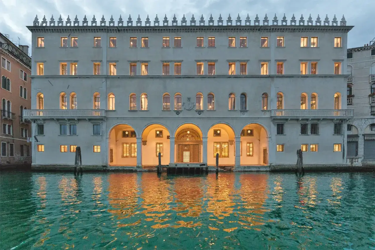 Il Fondaco dei Tedeschi a Venezia, con le sue arcate illuminate e il riflesso dorato sull'acqua, evoca un'atmosfera magica.