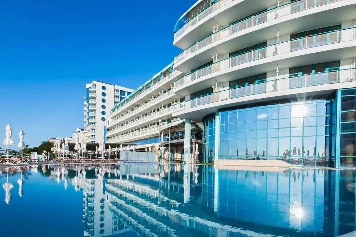 Luksusowy hotel z basenem i tarasami, odbijający się w wodzie. Idealne miejsce na wakacje na Złote Piaski Bułgaria.